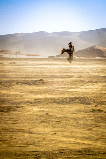 Woman standing in desert against sky