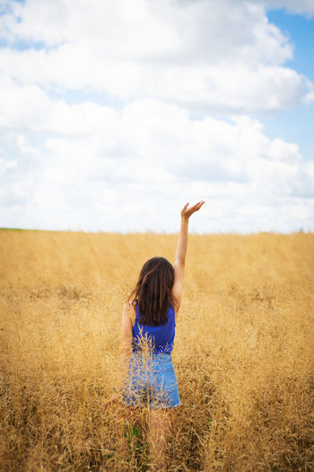 A girl in a blue t-shirt and denim shorts stands in the middle of a field
