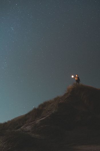 Low angle view of man on mountain against sky at night