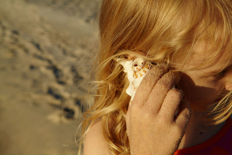 Close-up of girl listening through seashell