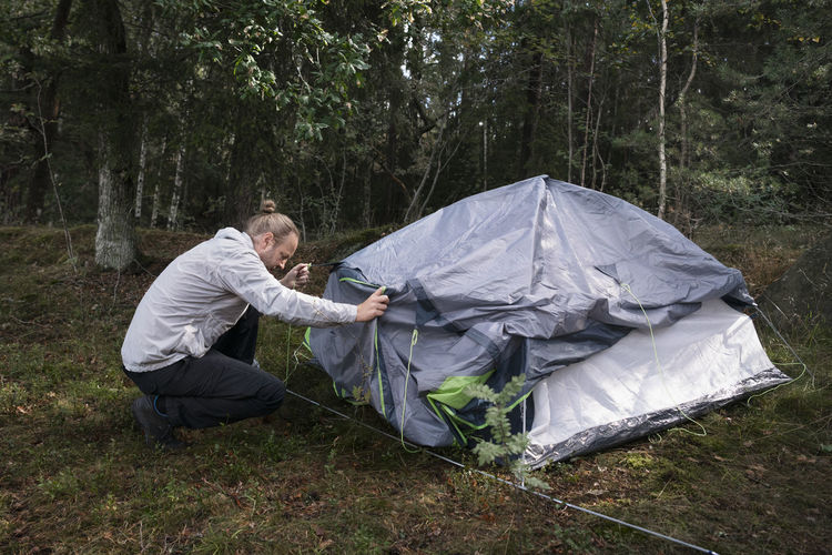 Man wild camping, setting up tent