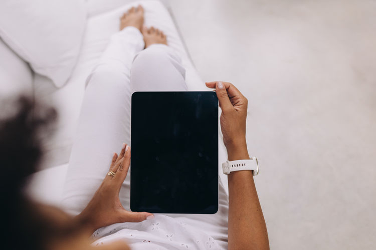 Black woman holding a digital tablet, over shoulder view