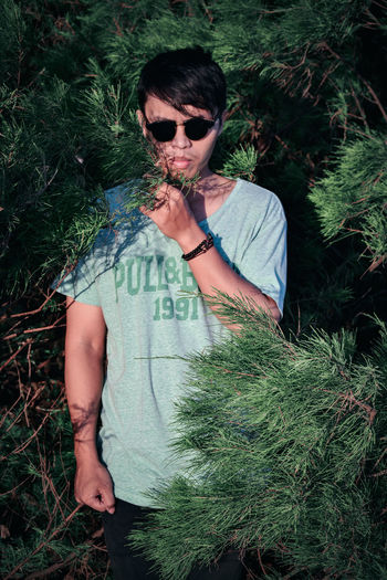 Young man wearing sunglasses amidst trees