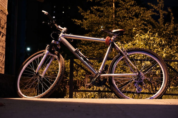Bicycle parked on street in city at night