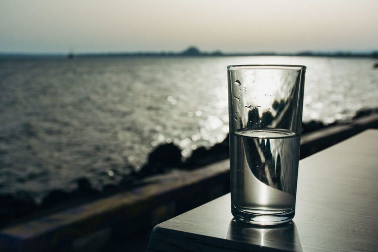 Glass of water on table against sea during sunset at pomorie