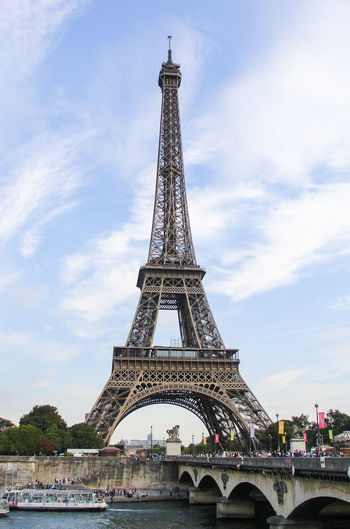 Eiffel tower by arch bridge over seine river against sky