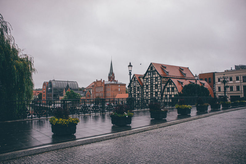 View of buildings by river against sky in city