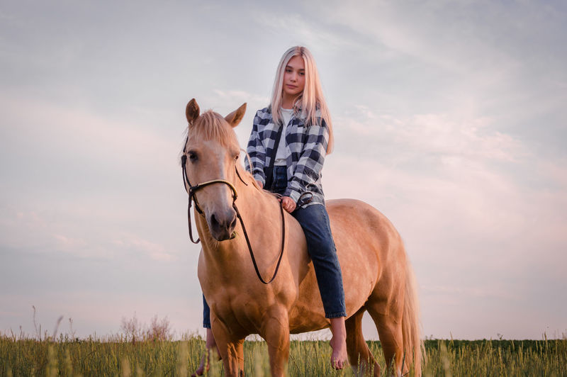 Young woman with horse against sky
