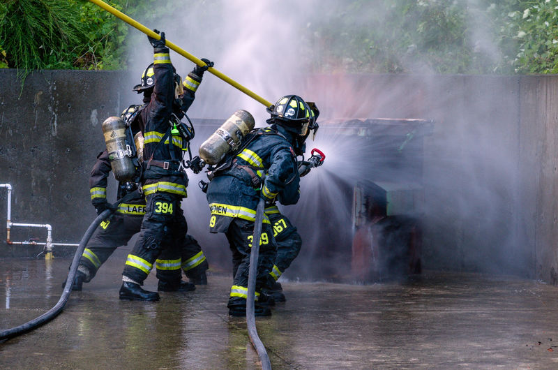 Rear view of firefighter using water hose