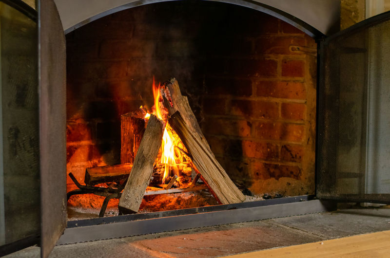 A bright orange fire burning in an old brick fireplace