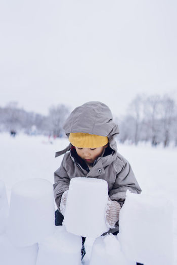 A boy playing ice bricks in a snowy winter