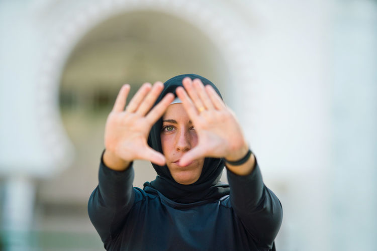 Portrait of young woman in hijab gesturing while outdoors