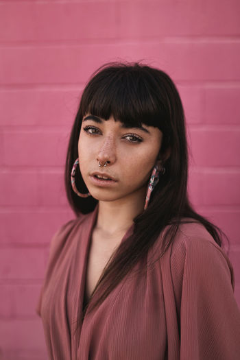 Portrait of beautiful woman standing against pink wall