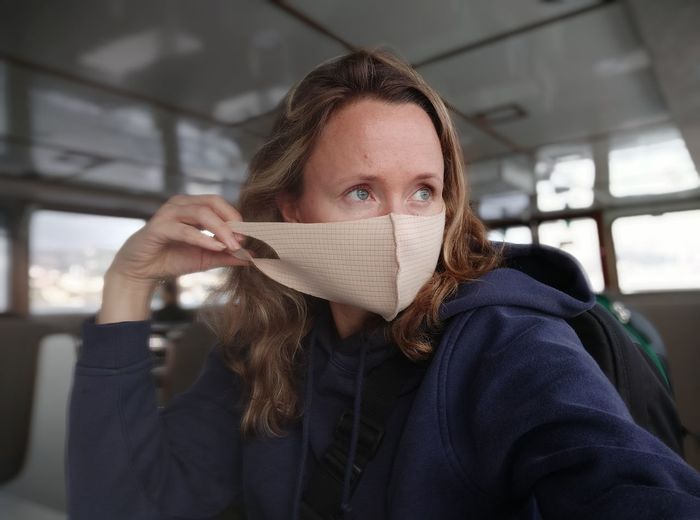 Woman wearing mask looking away while sitting in bus