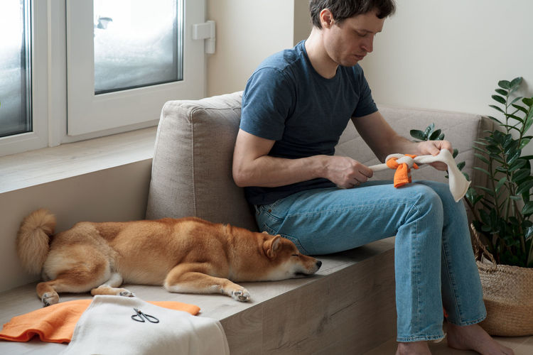 Adult man making diy homemade educational toys for dogs using a tutorial from the internet