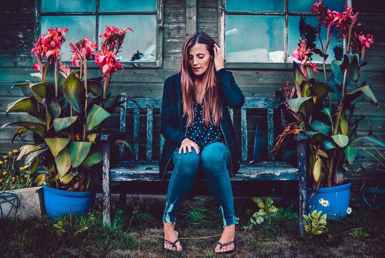 Portrait of beautiful young woman sitting by plants