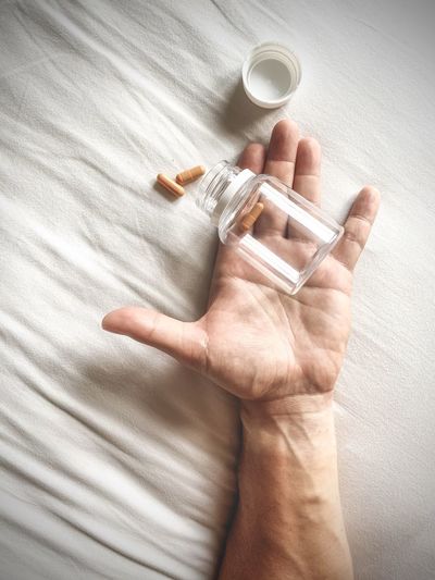 Close-up of human hand holding a bottle of pills 