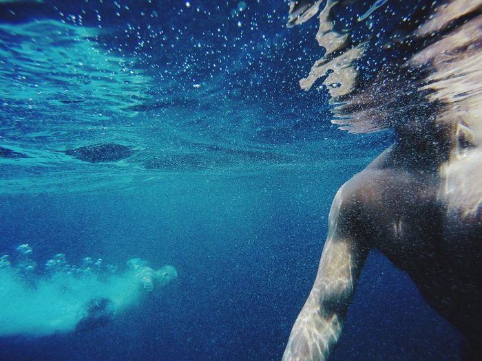 Close-up of shirtless man swimming in blue sea