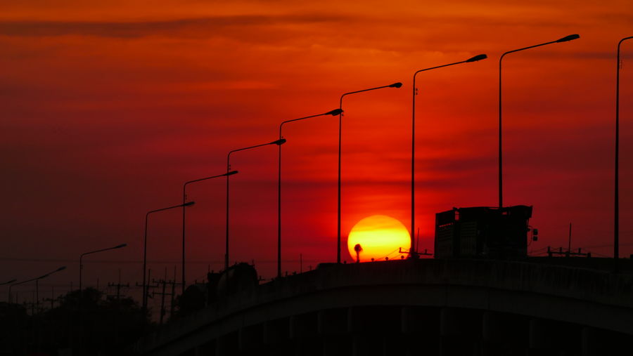 Low angle view of silhouette bridge against orange sky