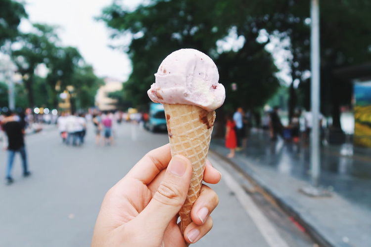 Cropped hand of person holding ice cream cone on street