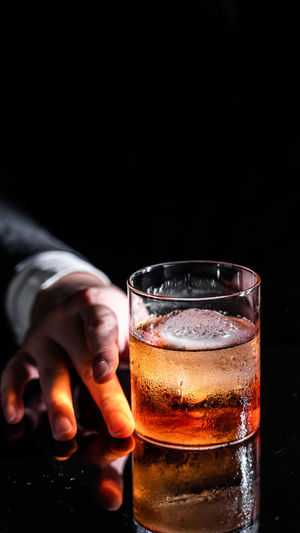 Midsection of man holding beer against black background