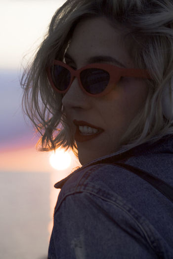 Close-up of beautiful young woman wearing sunglasses during sunset