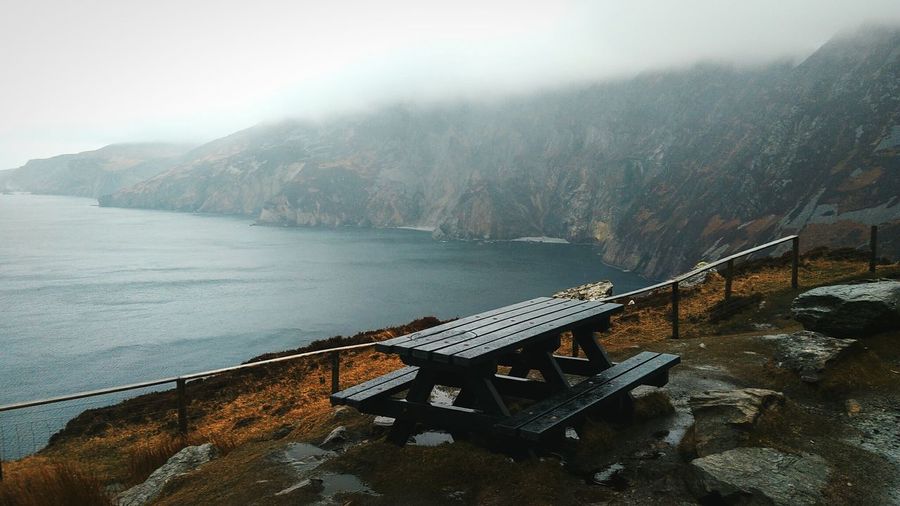 Empty bench on mountain by sea 
