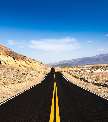 Empty road at desert against sky