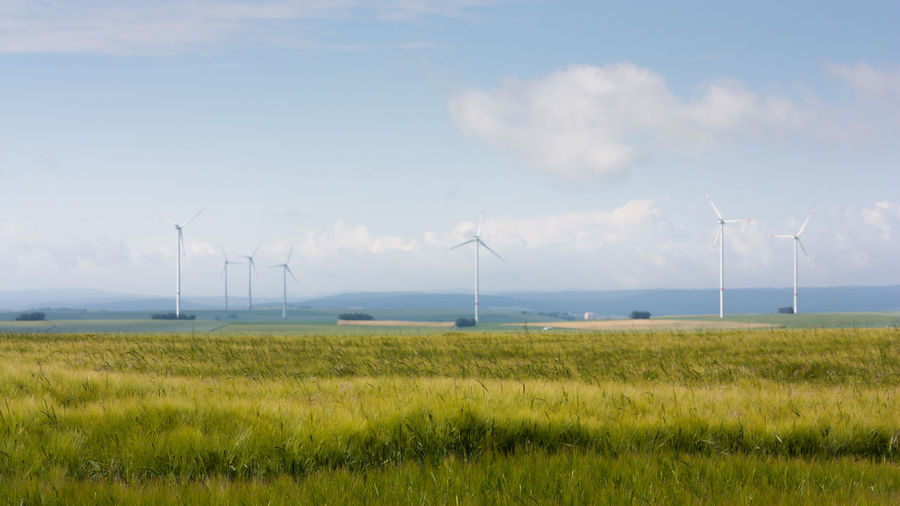 Wind turbines on field against sky