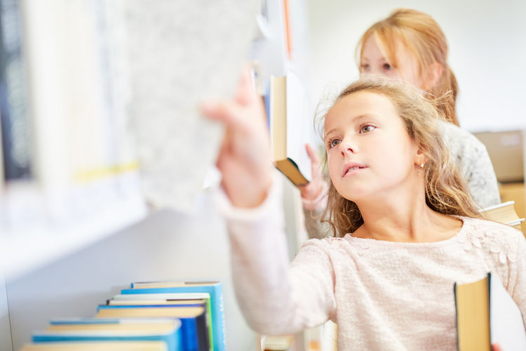 Girl choosing book while standing at library