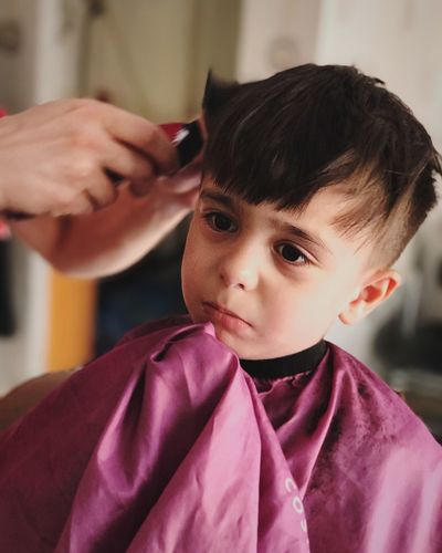 Cropped hands of barber cutting boy hair