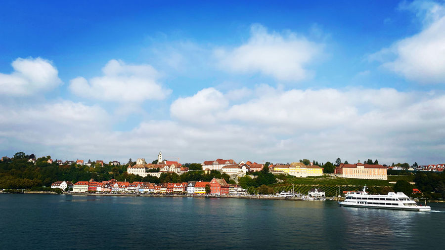 Buildings by river against sky in town