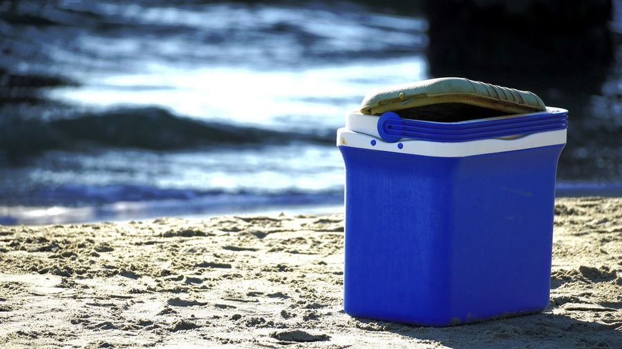 Close-up of blue container on beach