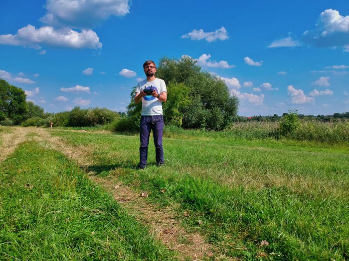 Man holding remote control while standing on land against sky