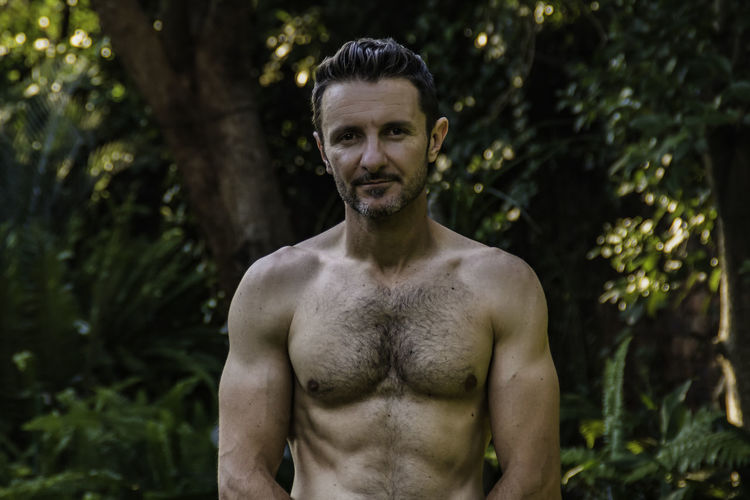 Attractive man in his forties, with his shirt off revealing his in form body. 