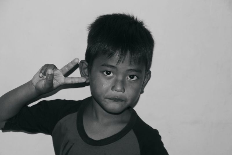 Portrait of boy holding camera against white background