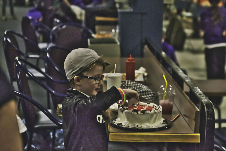 Side view of boy having cake at table in restaurant