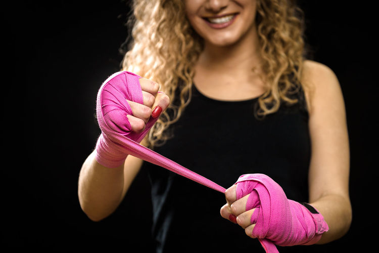 Midsection of woman with boxing ribbon standing against black background