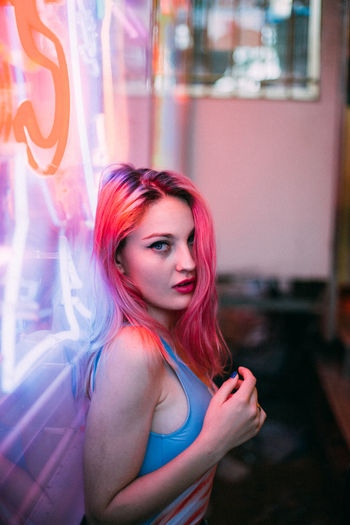 Young woman with pink hair against neon sign