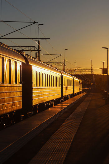 Train at railroad station against sky during sunset