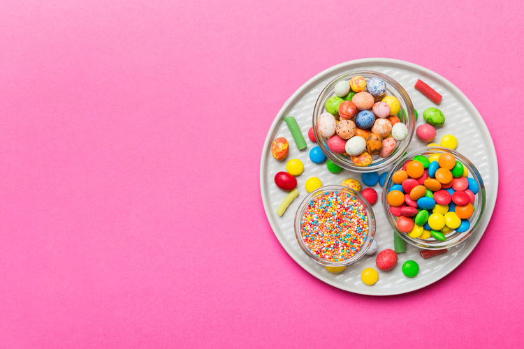 Directly above shot of candies in bowl against pink background