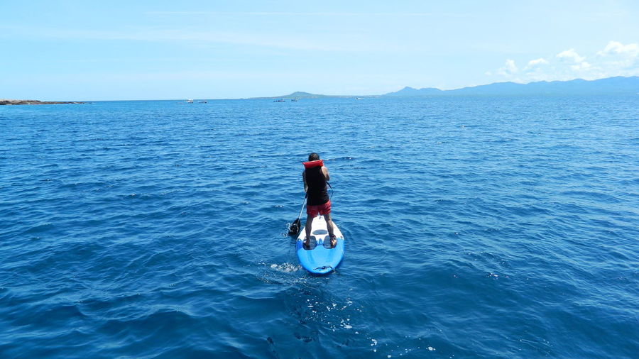 High angle view of man paddleboarding in sea against sky