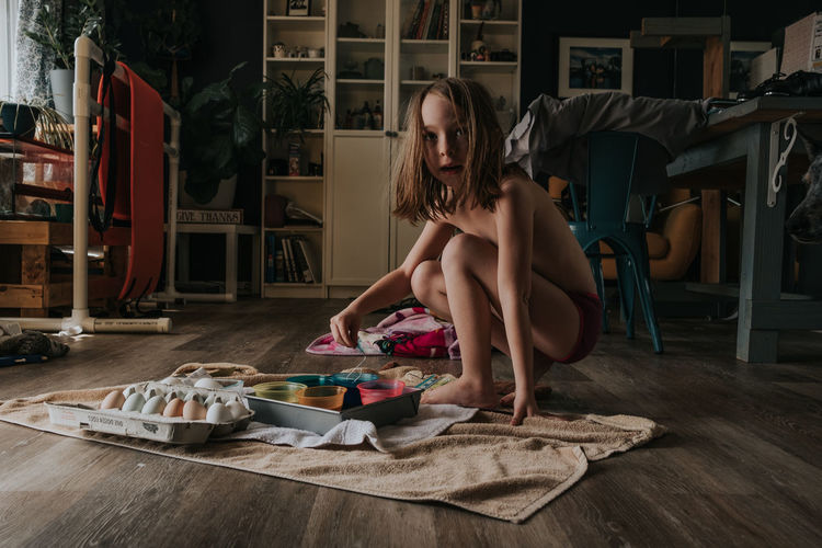 Young girl coloring easter eggs alone in a room
