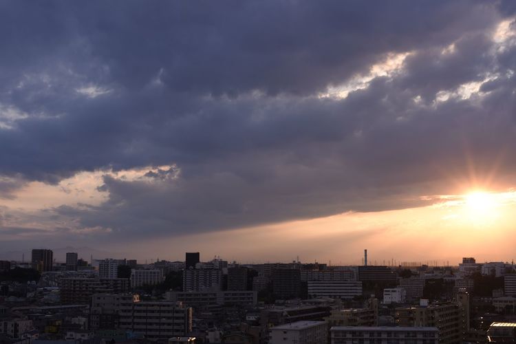 Cityscape against cloudy sky at sunset