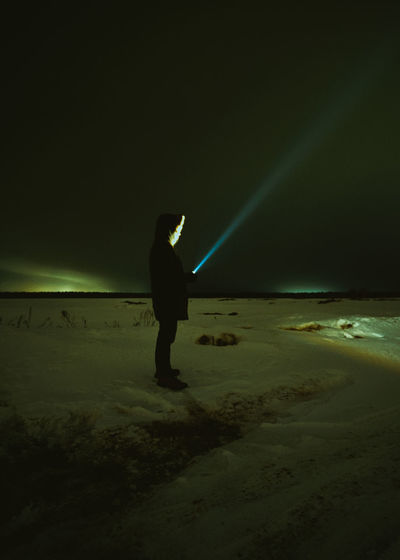 Rear view of woman walking on road at night