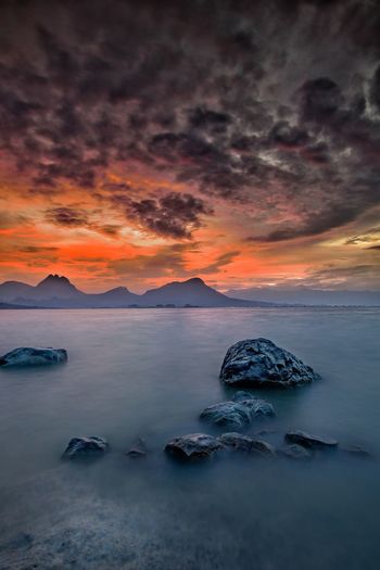 Scenic view of sea against dramatic sky during sunset