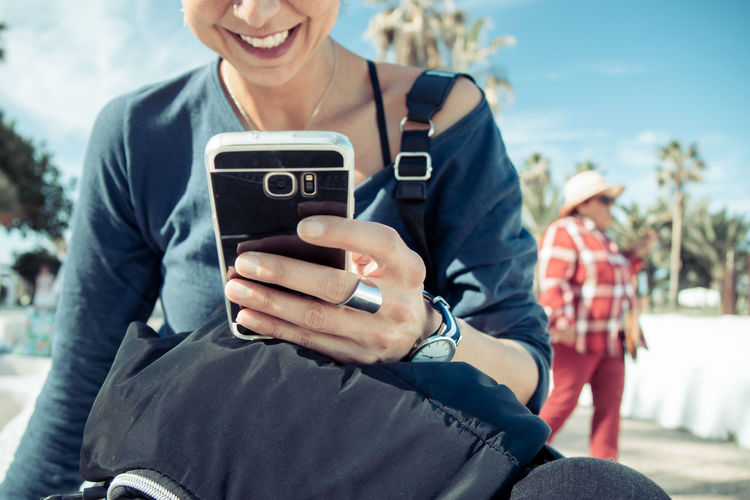 Midsection of woman using mobile phone while sitting outdoors