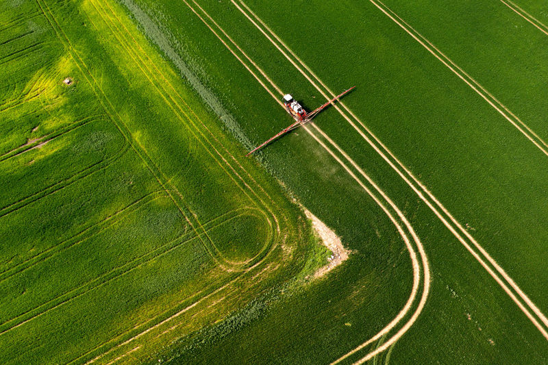 Top down view of the tractor spraying the chemicals on the large green field