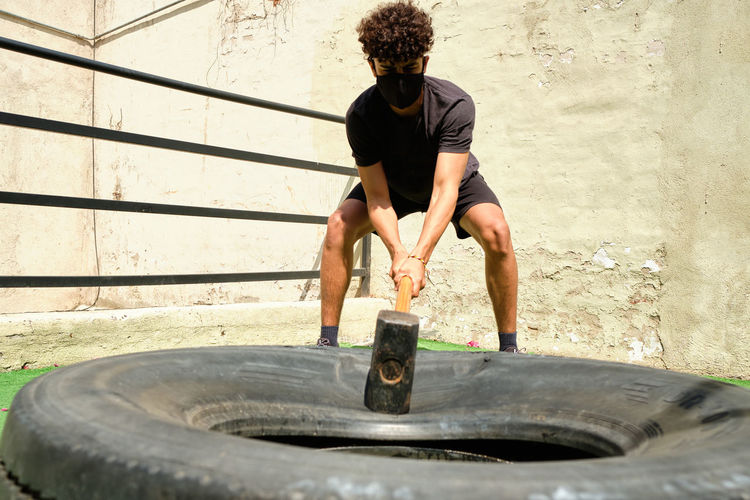 Man smashing hammer against wheel training fit and healthy