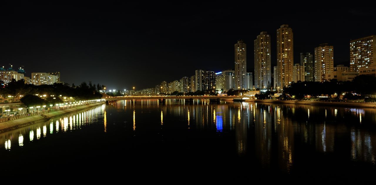 ILLUMINATED BUILDINGS BY RIVER AGAINST SKY